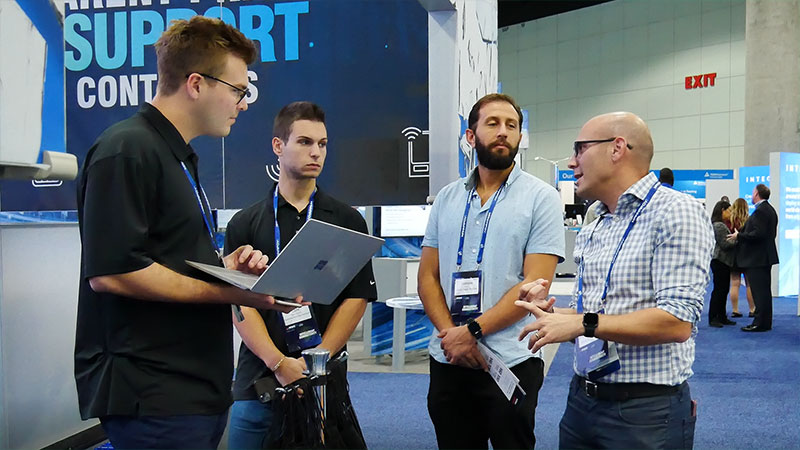 SIMON IoT employees meet with potential customers outside booth at tradeshow in California